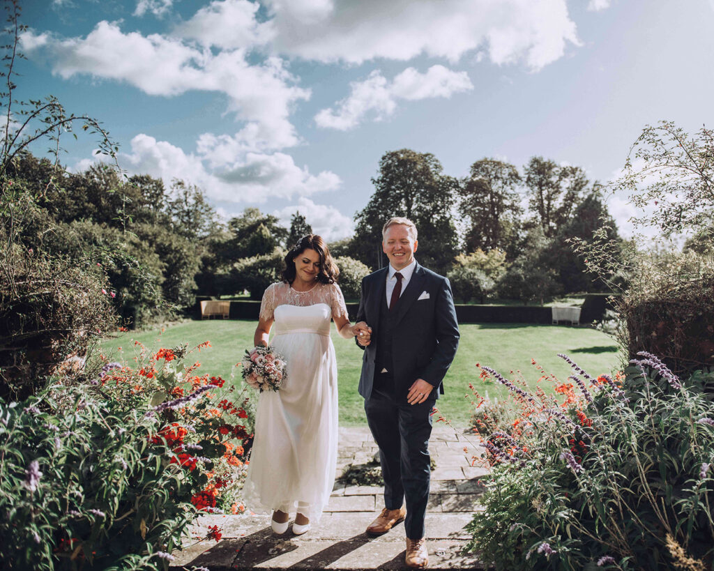 Elegant couple walking through a stately home garden in Kent on their wedding day