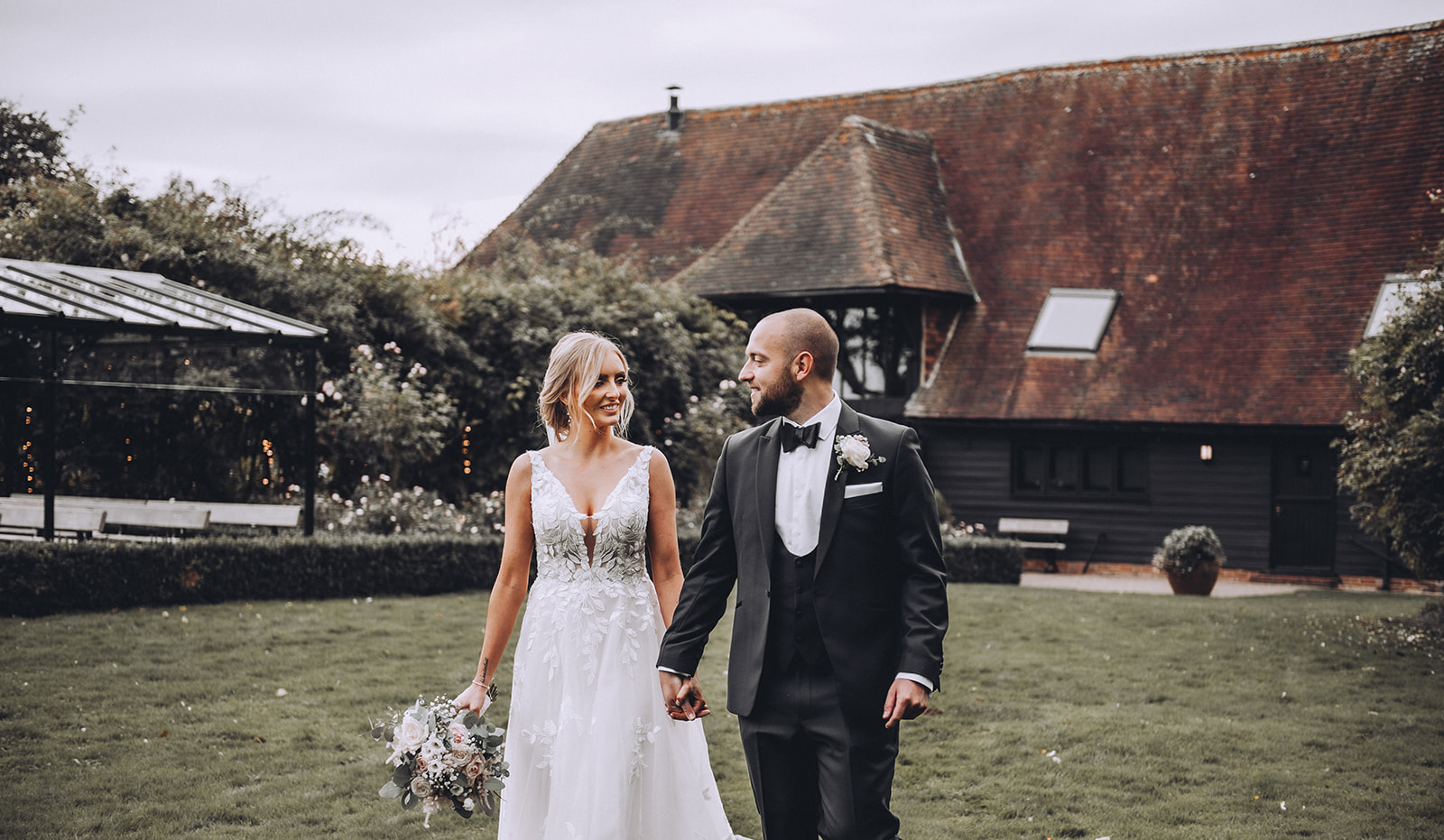 Bride and Groom walking across the grass at the Old Kent Barn