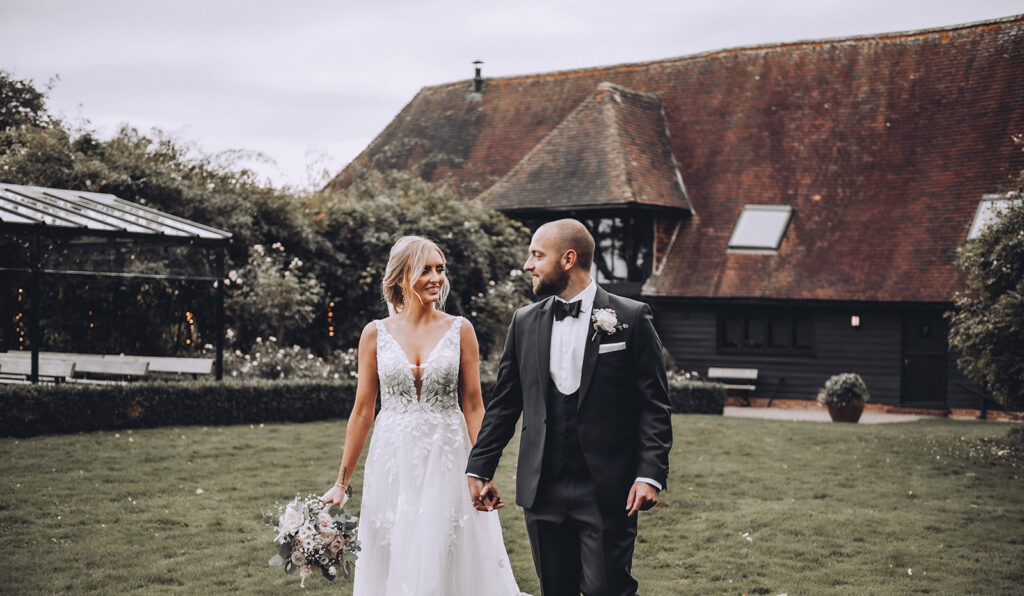 Bride and groom walking in front of TOKB at a luxury barn wedding in Kent