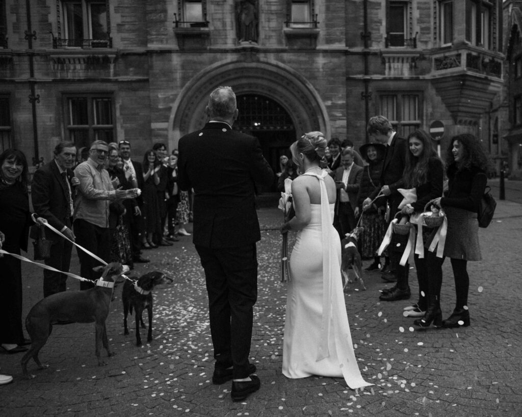 Bride and groom during confetti outside Gonville & Caius College in Cambridge
