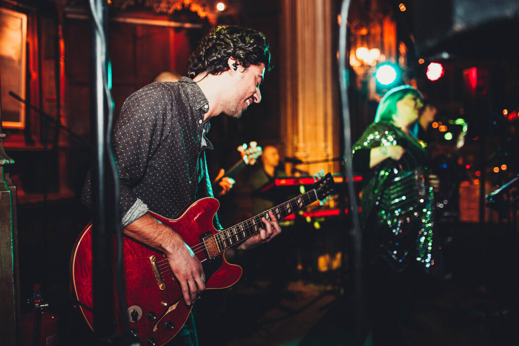 Guitarist playing a red Gibson ES335 at a wedding at Kings College