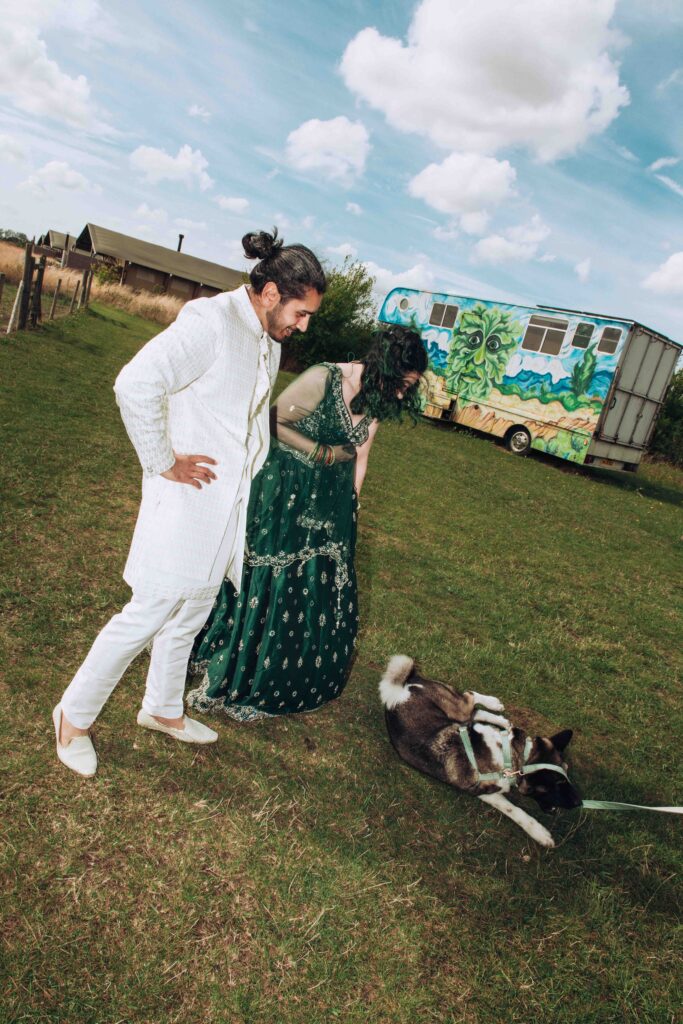 Indian bride and groom watching their dog roll around at their vegan wedding in Kent