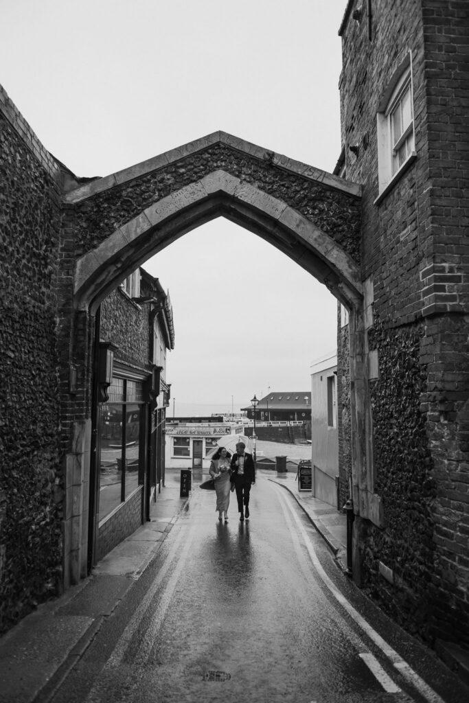 Bride and groom walking holding umbrellas in Broadstairs