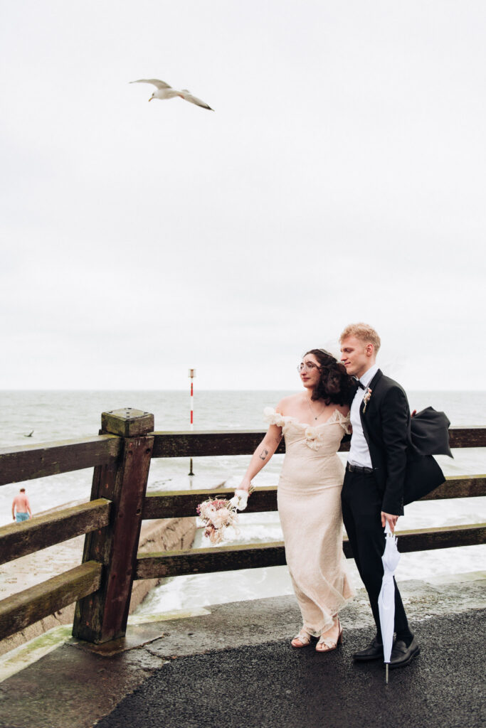 Bride and groom stood by the sea in Viking Bay in Broadstairs with a seagull