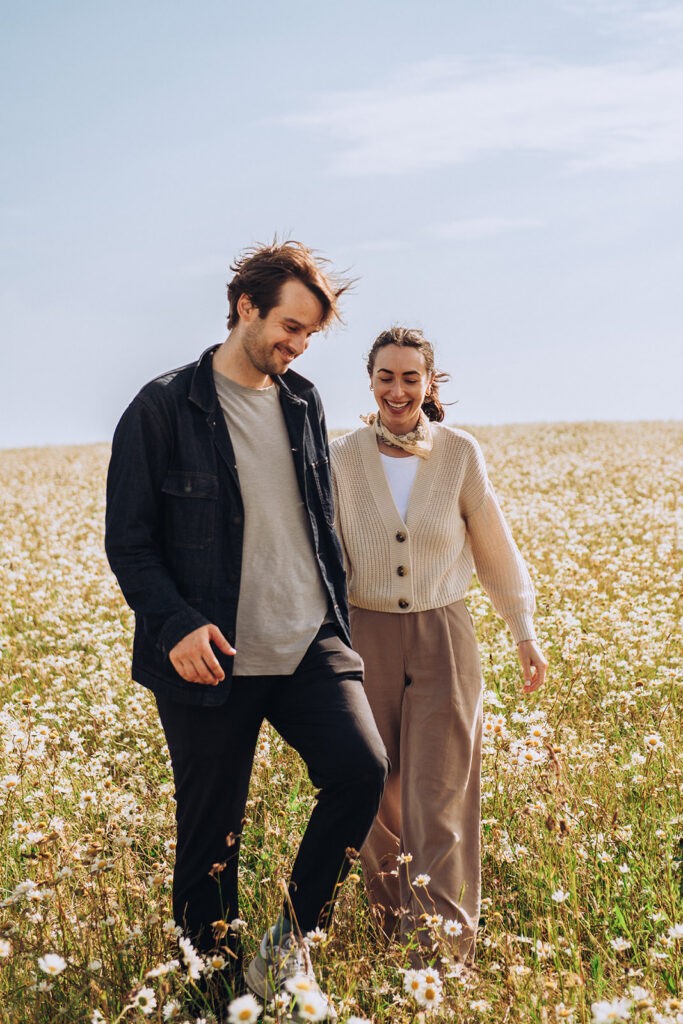Newly engaged couple walking by Joss Bay daisy fields