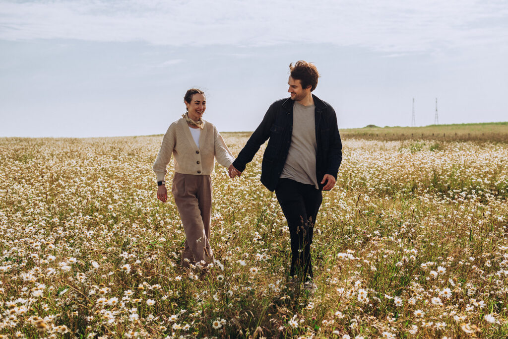 Newly engaged couple walking by Joss Bay fields