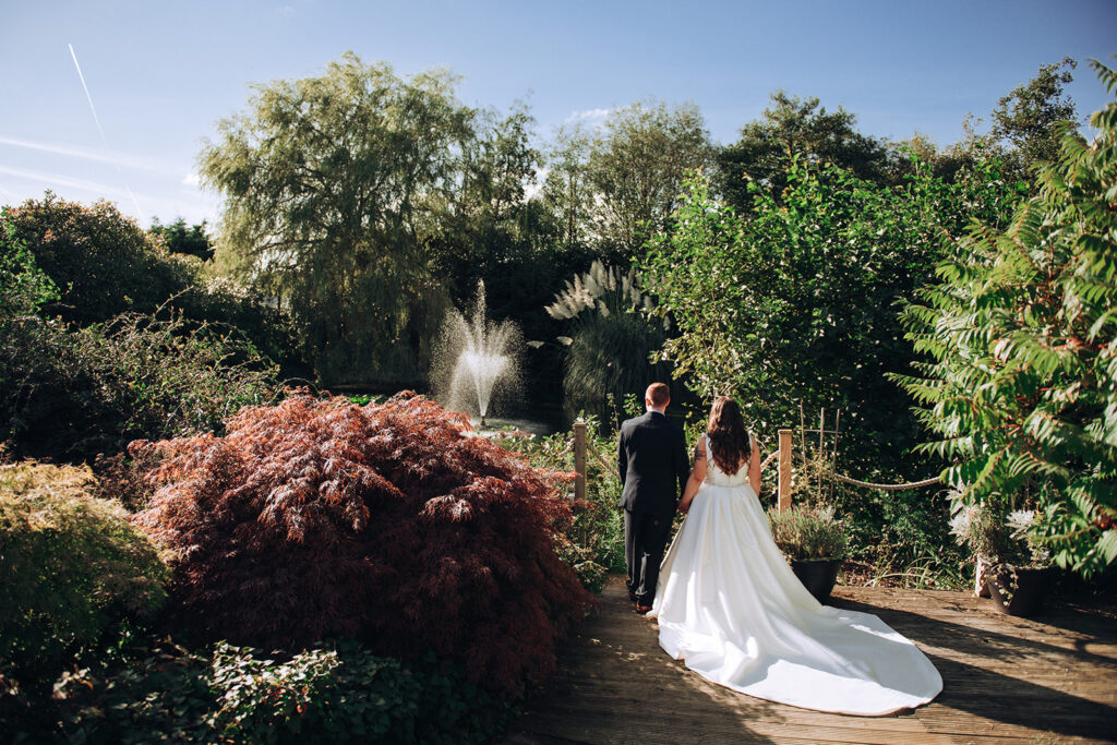 Bride and groom stood by pond in The Old Kent Barn