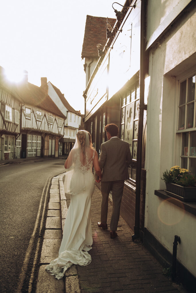 Bride and groom walking through Sandwich on their wedding day during sunset