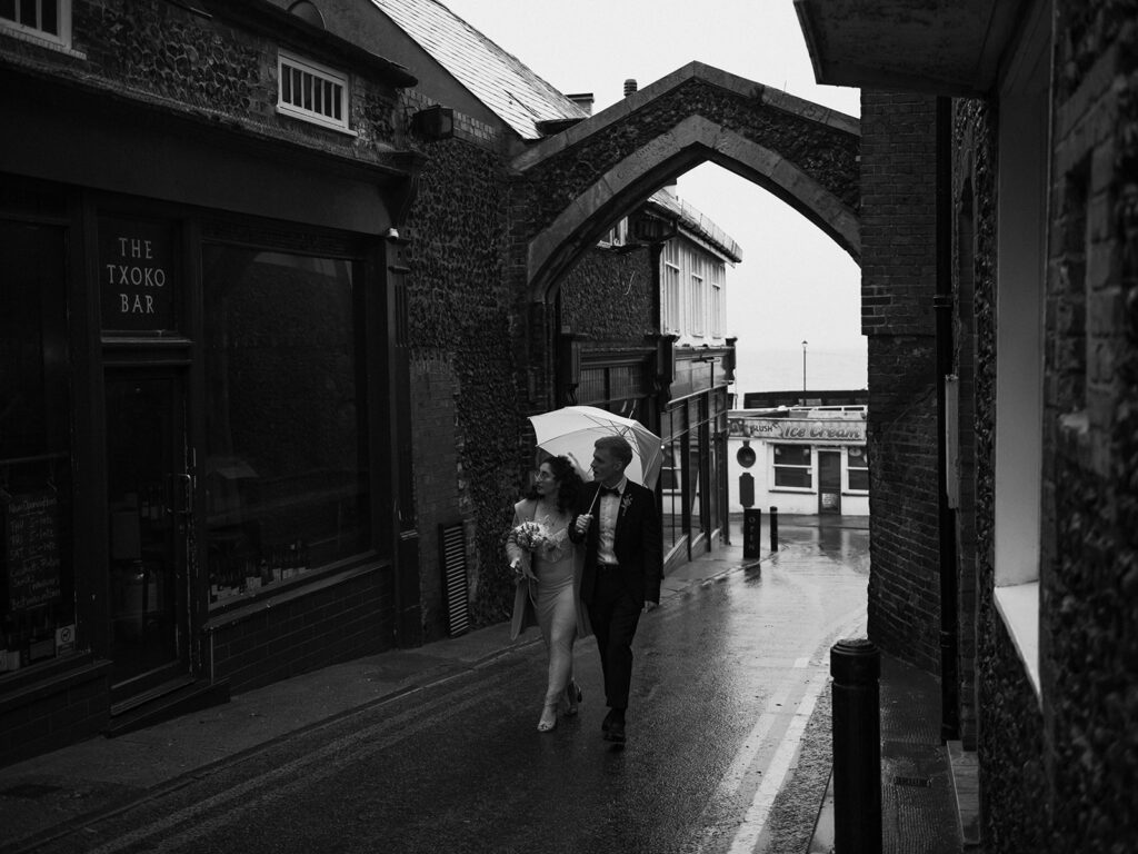 Bride and groom walking on road in Broadstairs during the rain