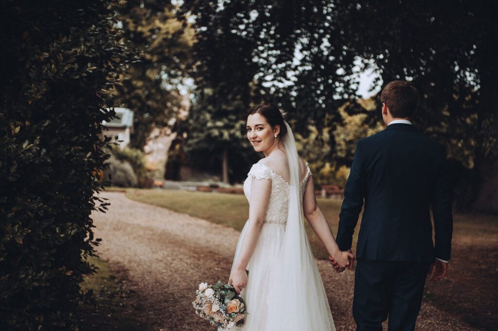 Groom and bride turning around holding bouquet of flowers and walking with elegant church wedding photography