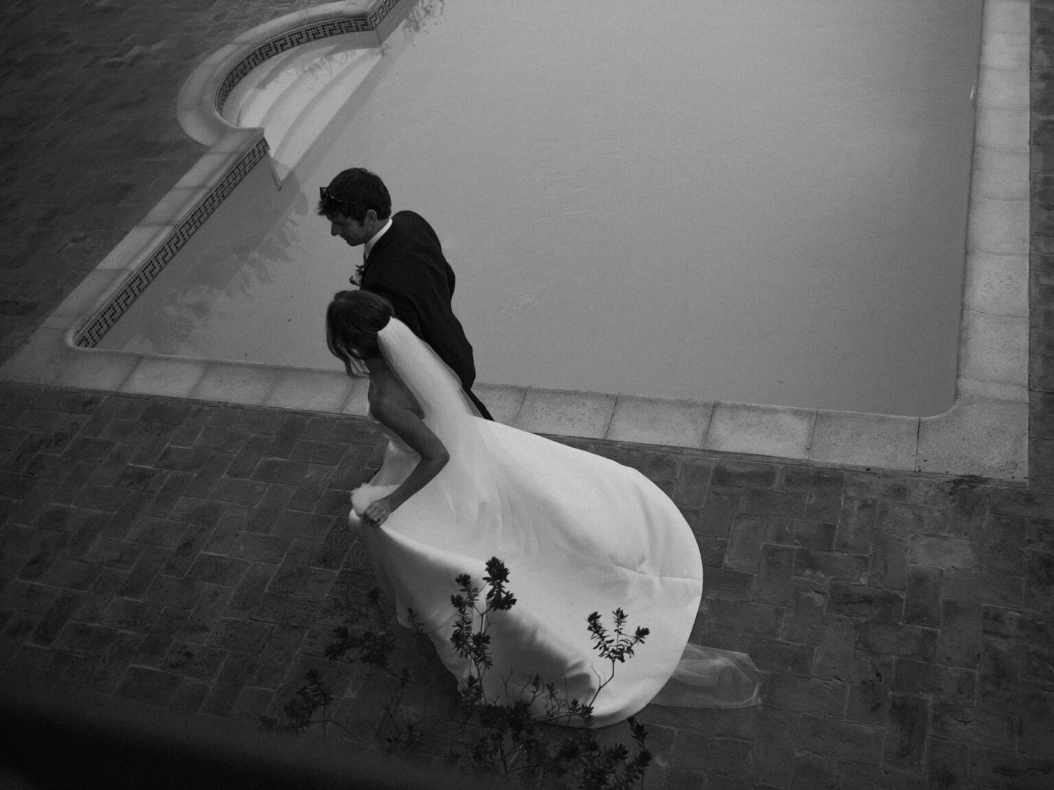 Editorial portrait of a couple walking by the pool at their wedding at Borgo di Tragliata in Rome