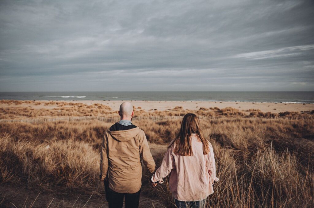 Couple holding hands on the beach in Norfolk photographed by Cambridge Photographer Tom Keenan