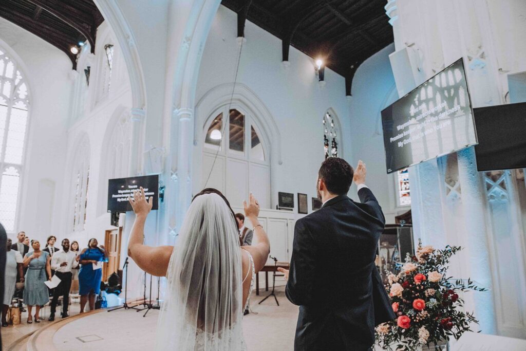 Bride and groom worshipping side by side at their wedding at Holy Trinity Church in Cambridge