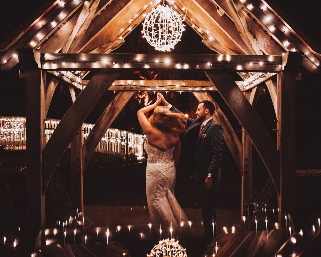 Bride and groom dancing underneath fairy lights