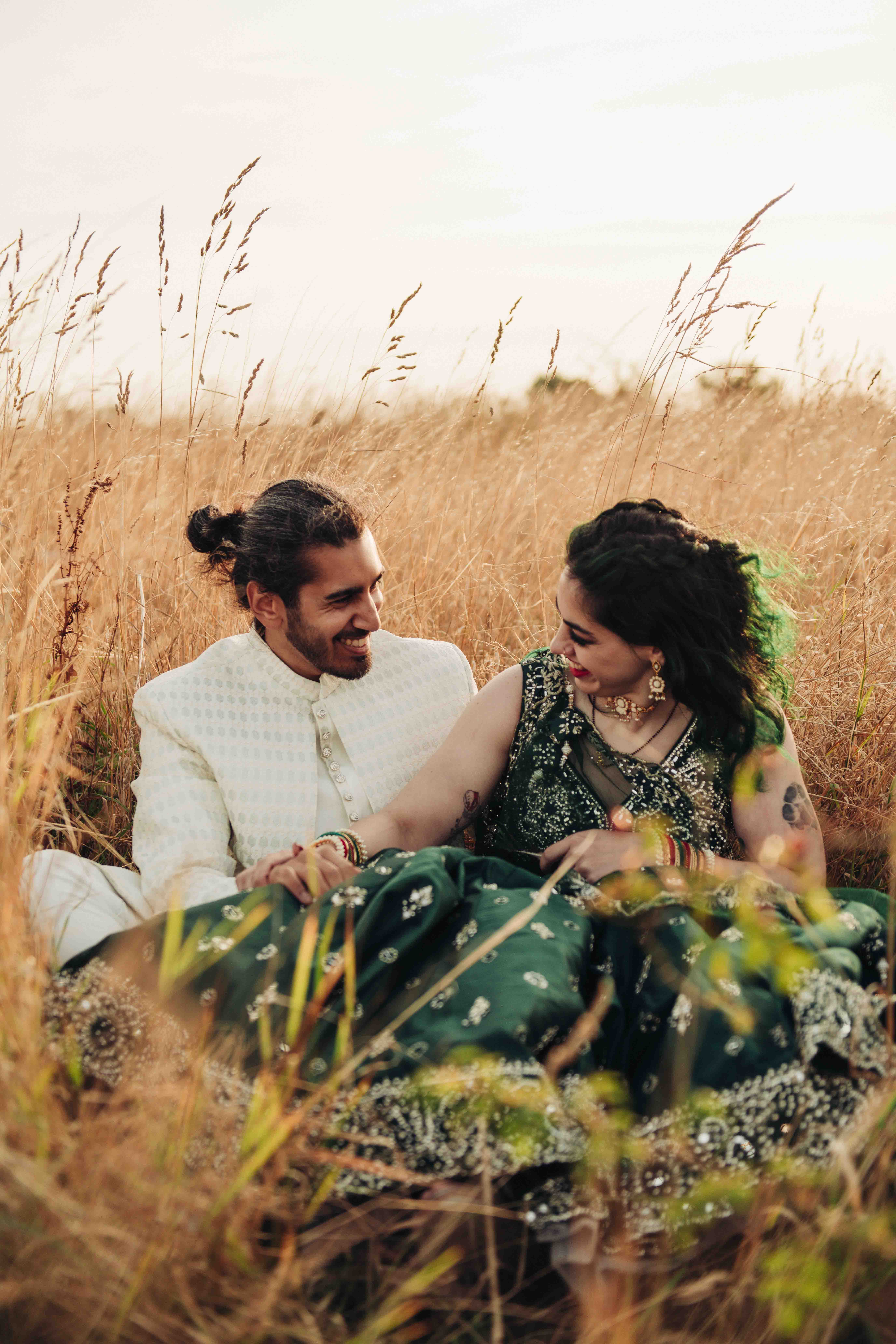 Portrait of bride and groom sat in field
