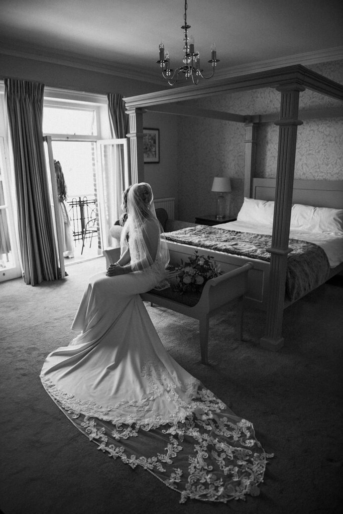 bride sat on a chair by a 4 poster bed