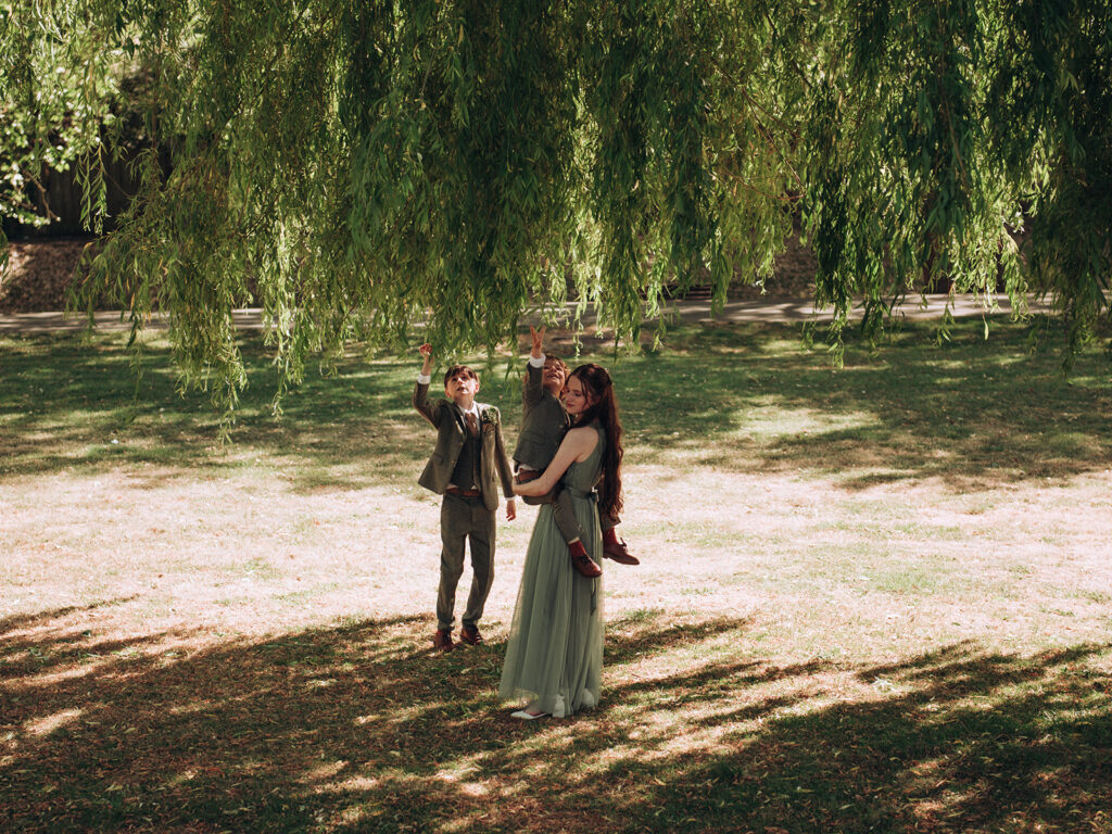 Children reaching up at willow tree