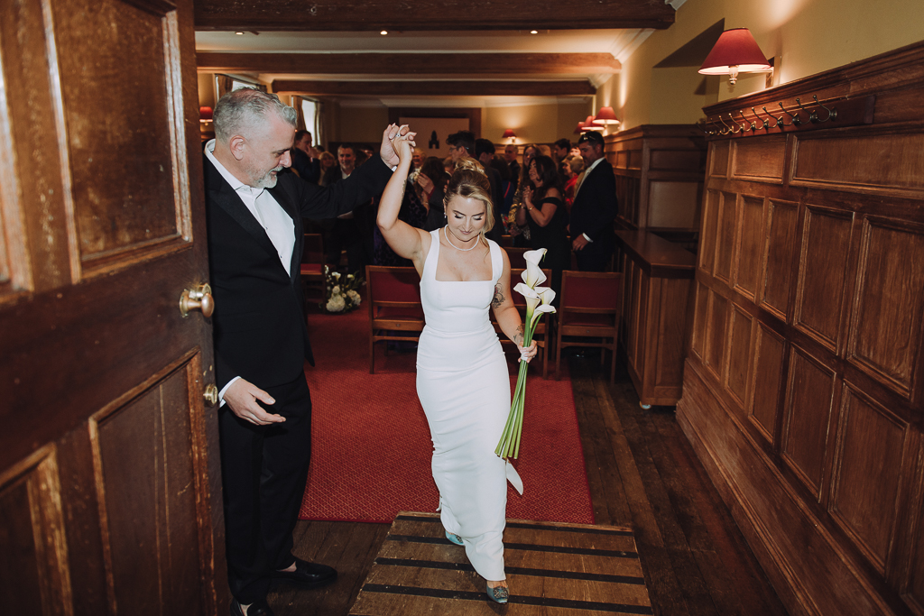 Bride and groom walking out of ceremony at gonville & caius college