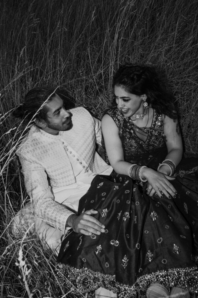 Direct flash portrait of bride and groom sat in field