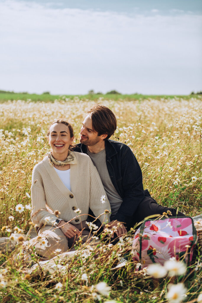 Newly engaged couple cuddling on picnic blanket