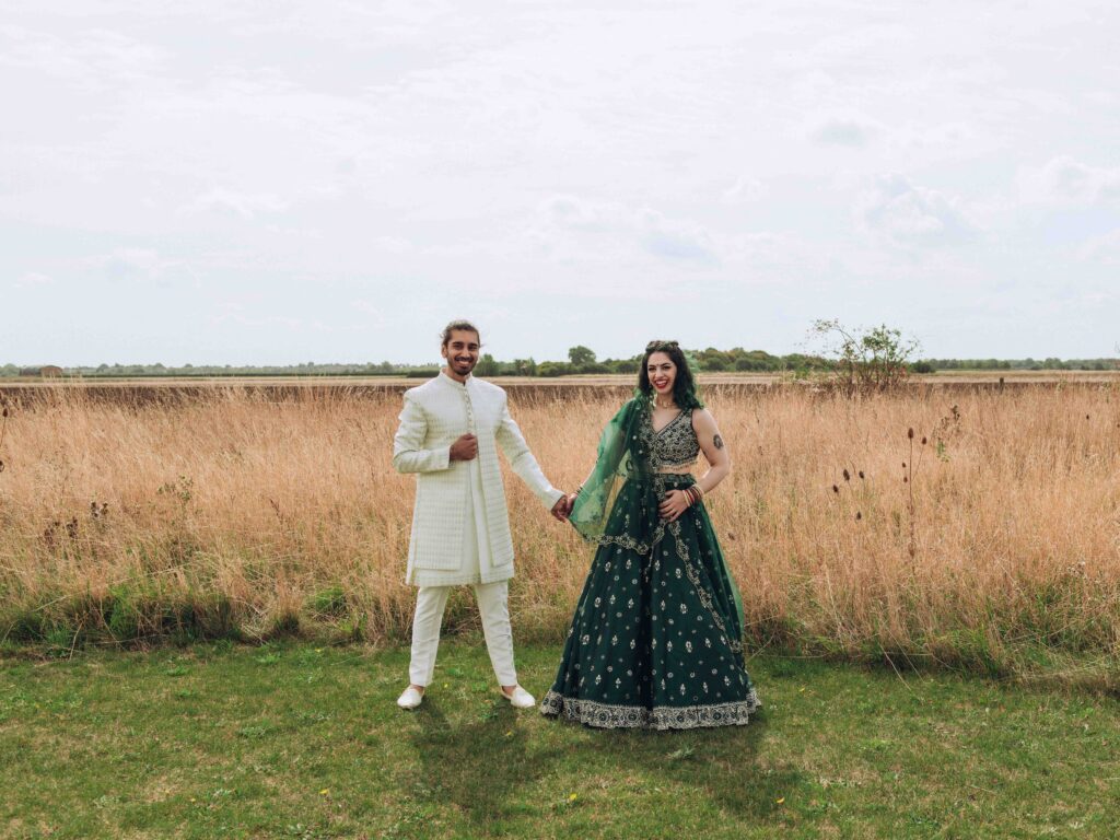 Bride and groom holding hands in field