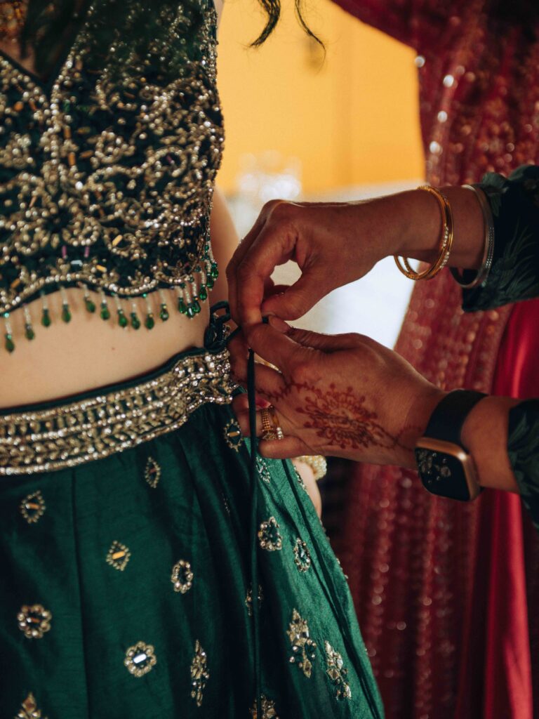 Indian henna on a mother's hand helping daughter into wedding dress