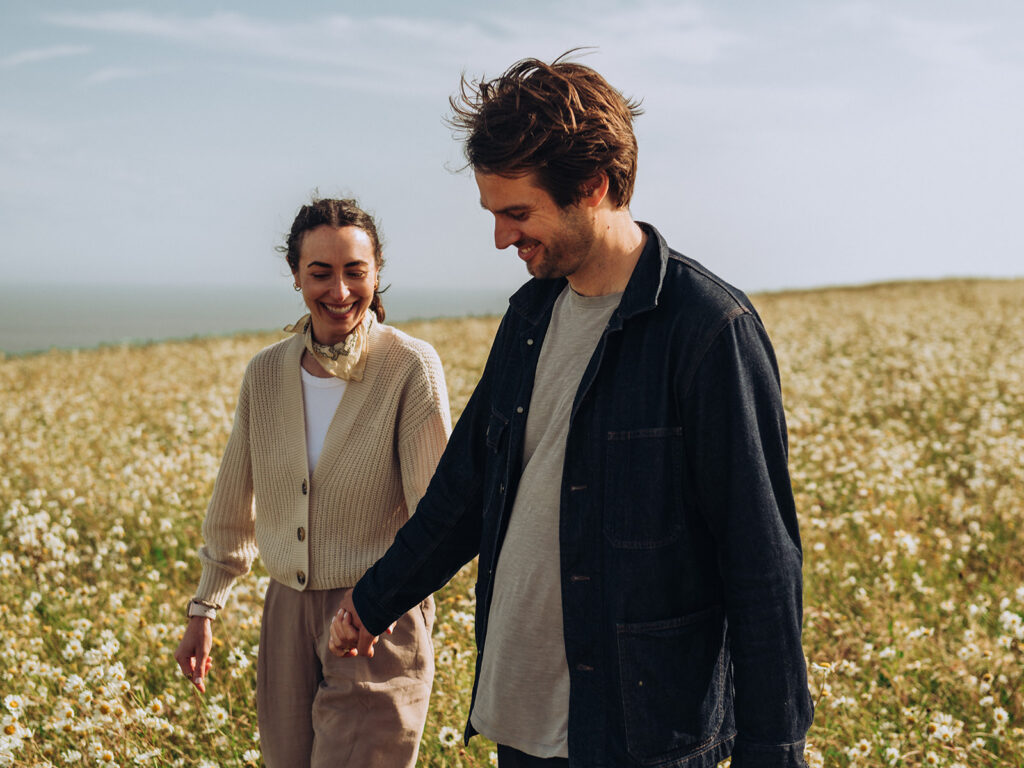 Young couple walking in field of daisies
