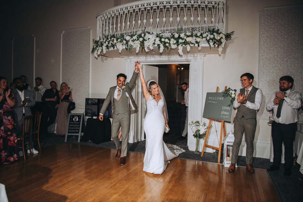 Newlyweds entering dancefloor hand in hand
