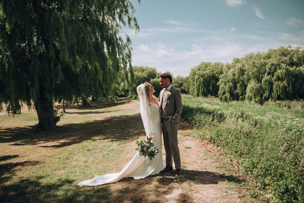 Bride and groom beside willow tree