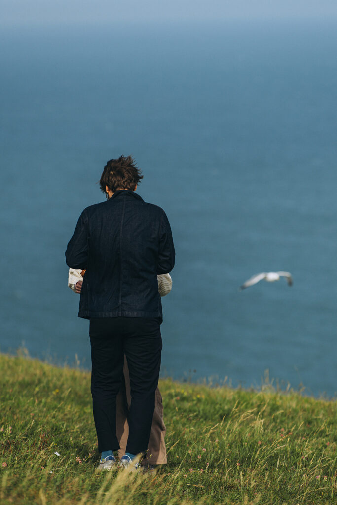 Seagulls flying past newly engaged couple on a cliff