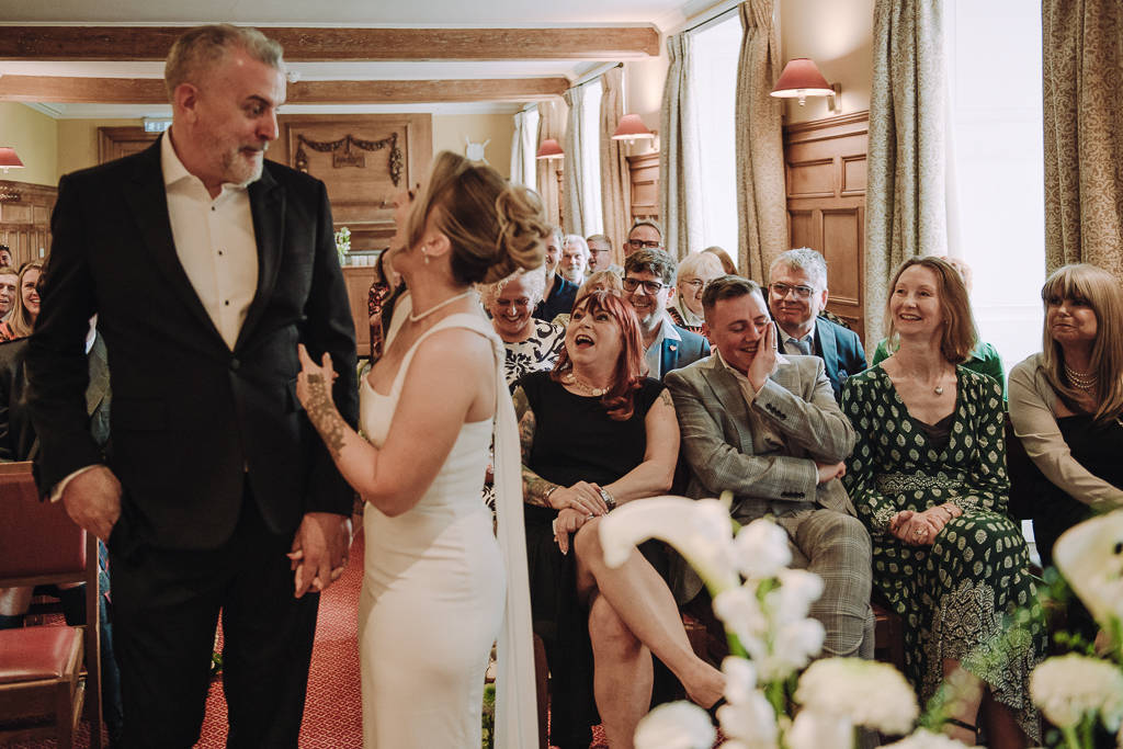 Bride and guests laughing in gonville & caius college