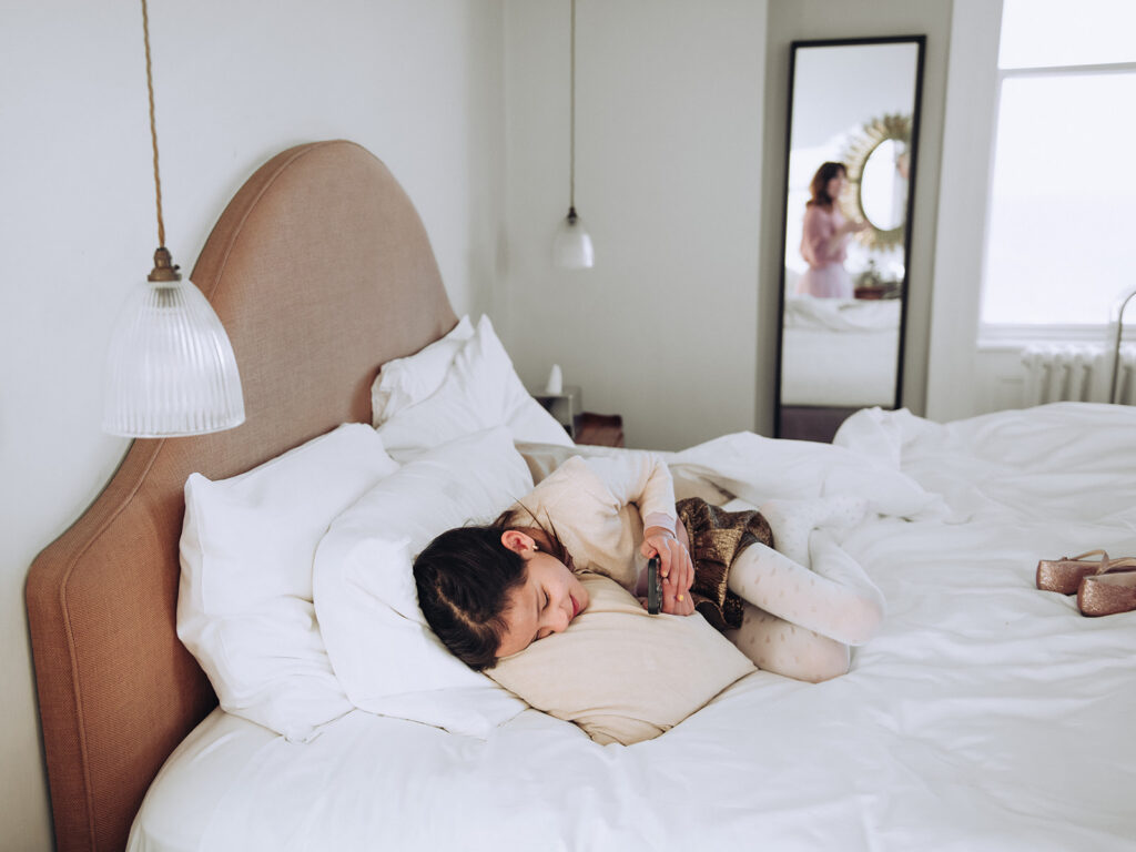 daughter on her phone laying on bed