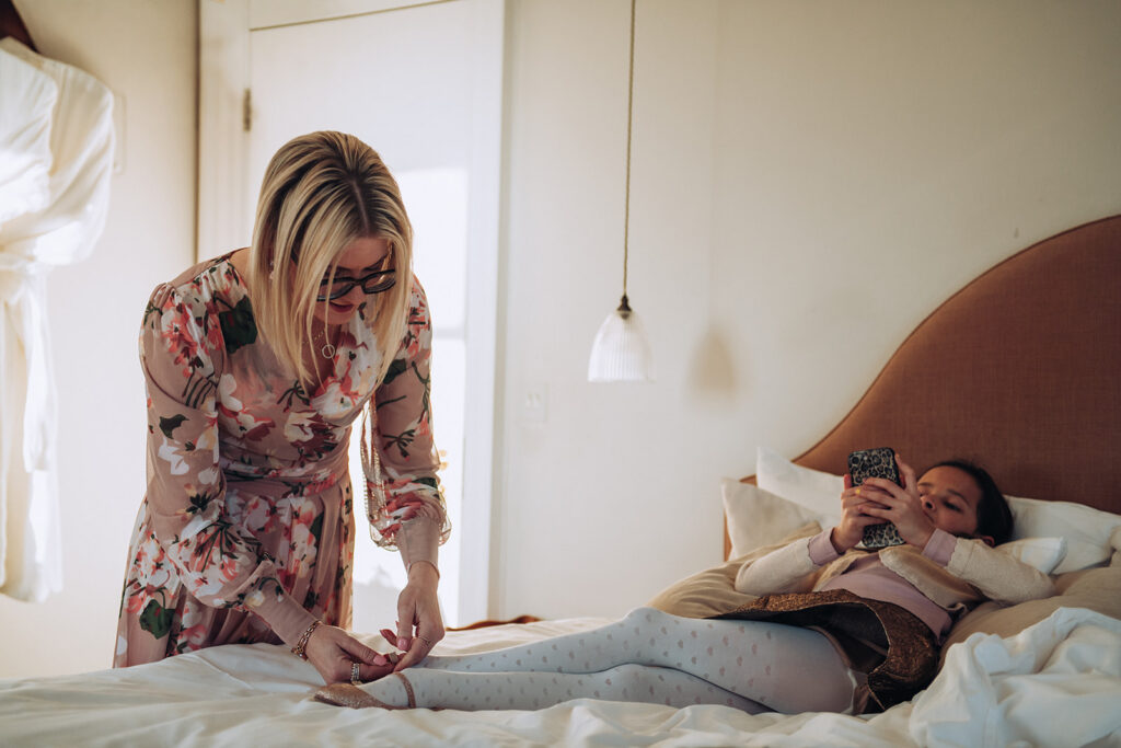 Bride putting on her daughters shoes at wedding