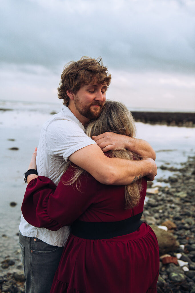 Newly engaged couple hugging on a beach