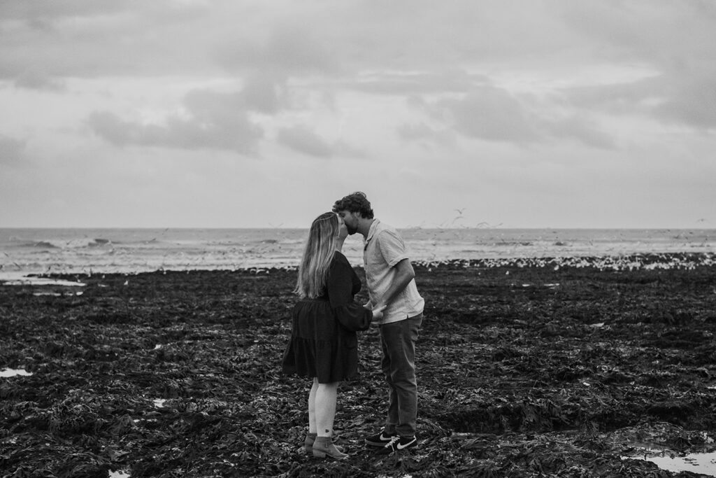 Newly engaged couple kissing on the beach