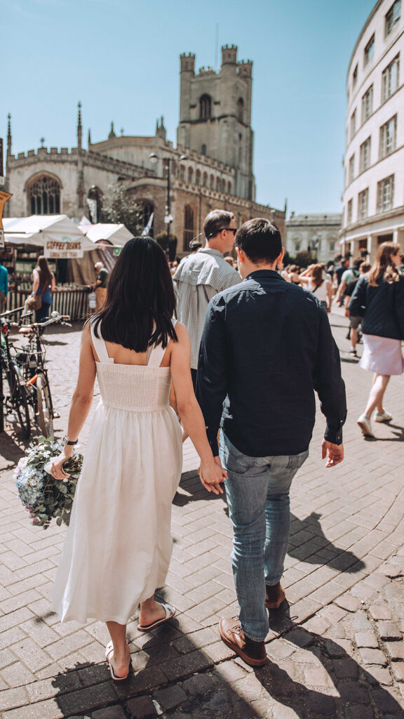 Couple walking through a busy street holding hands considering the tips they have learnt for their wedding budget