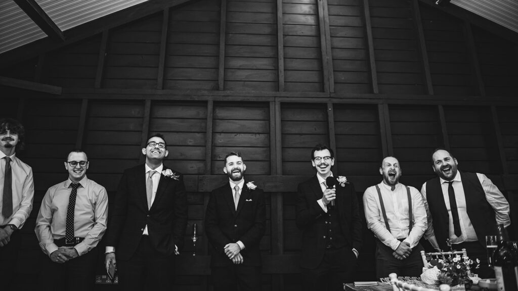 Groomsmen laughing at a wedding speech.