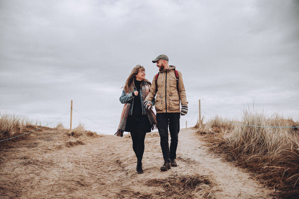 Walking down a sand dune enjoying quality time during a couple shoot by Tom Keenan Photography