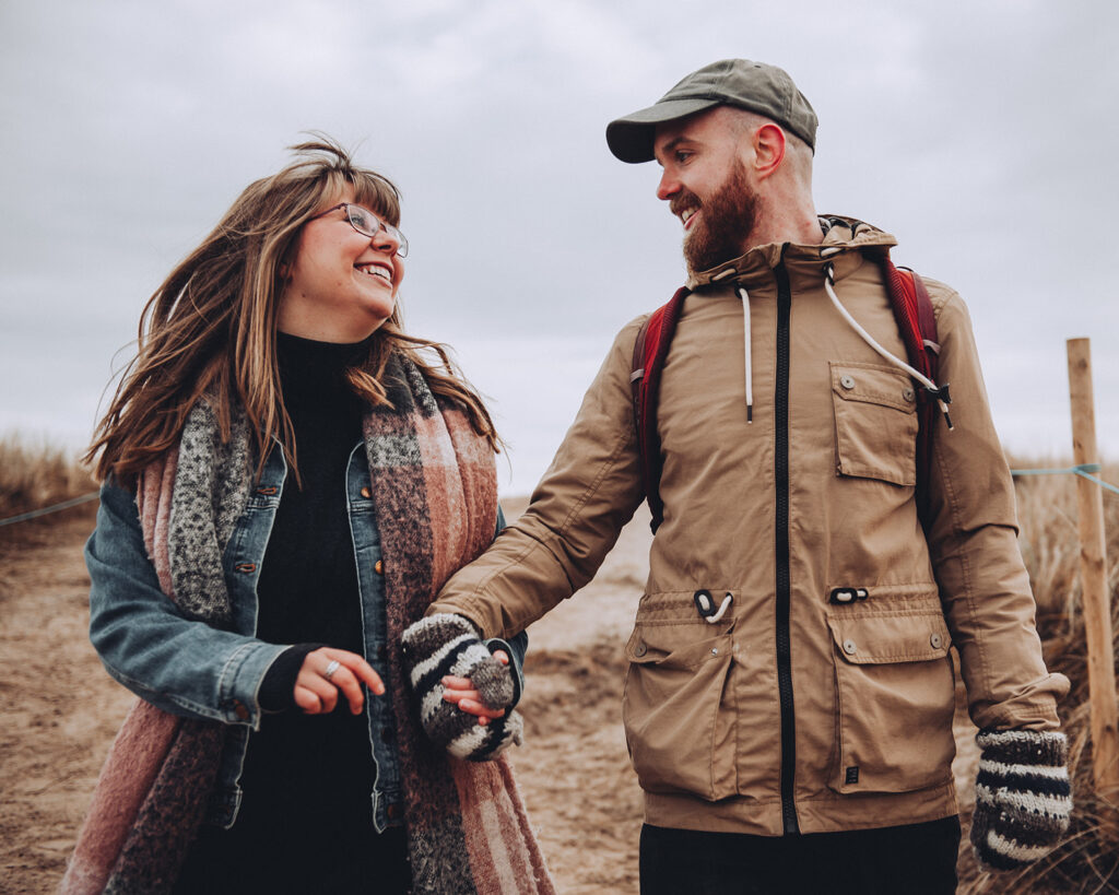 Couple running down sand dunes in Norfolk