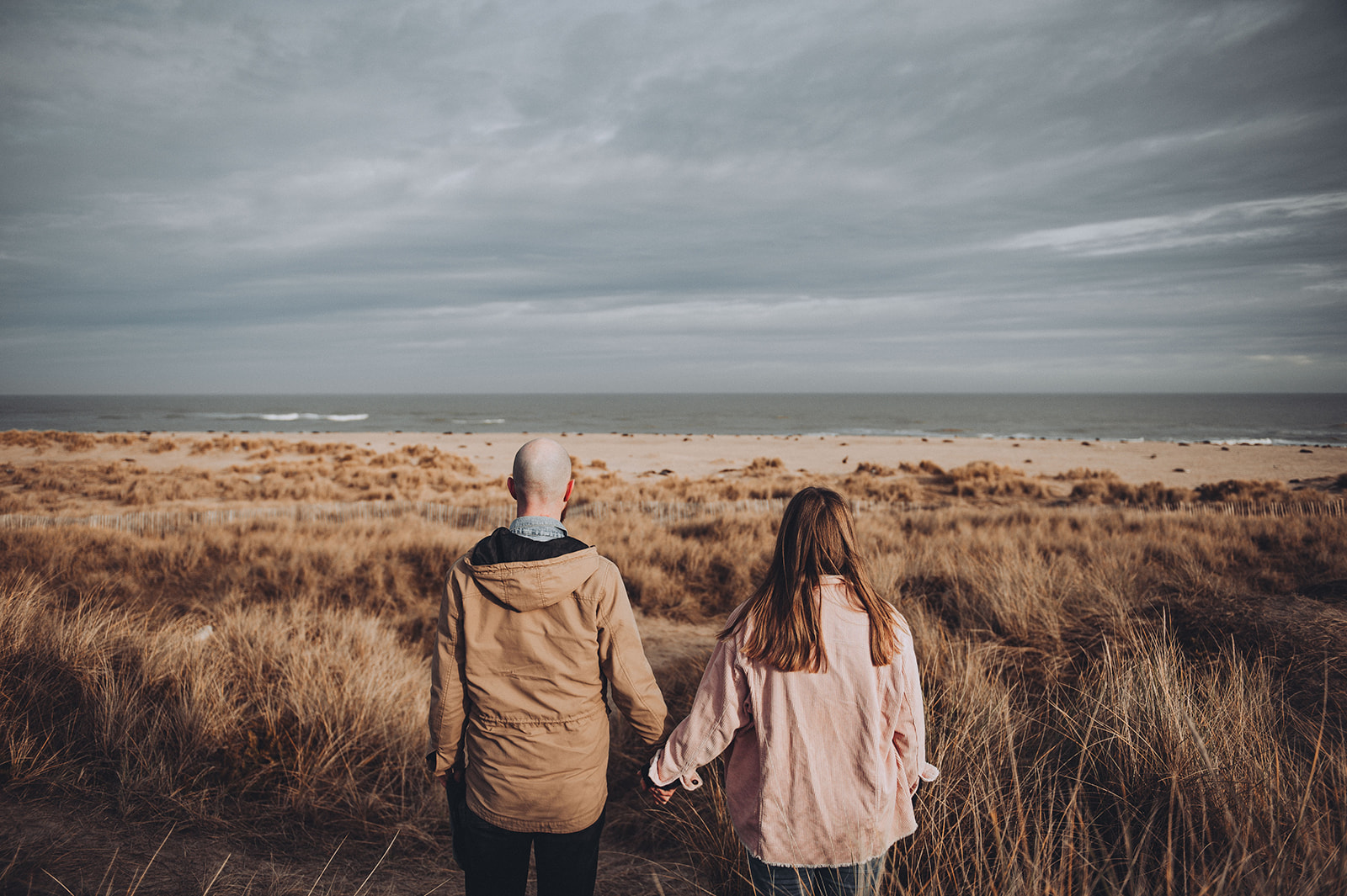 Couple holding hands on the beach in Norfolk photographed by Cambridge Engagement Photographer Tom Keenan