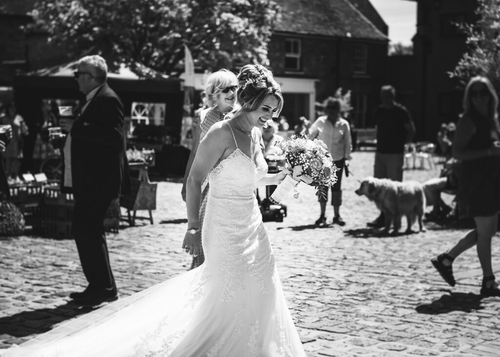 Bride smiling to herself outside the ceremony at her summer wedding in Sandwich, Kent.