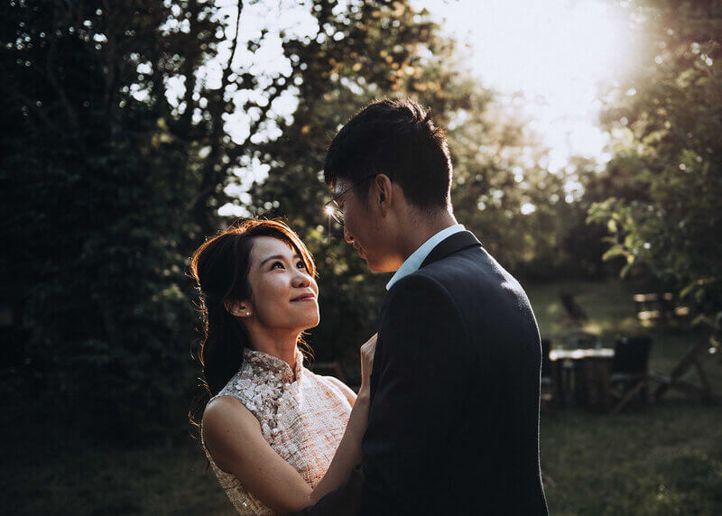 Engaged couple sharing an intimate gaze in a sunlit garden.