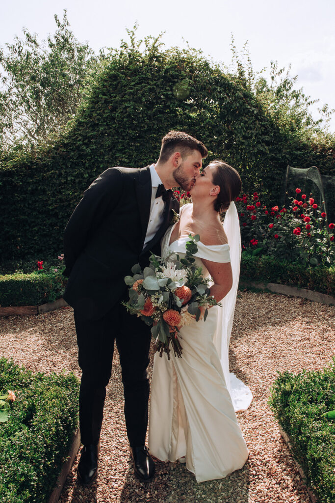 A couple kissing in the garden of the their luxury wedding venue, behind the scenes of Editorial Wedding Photography: A Luxury Couple's Shoot