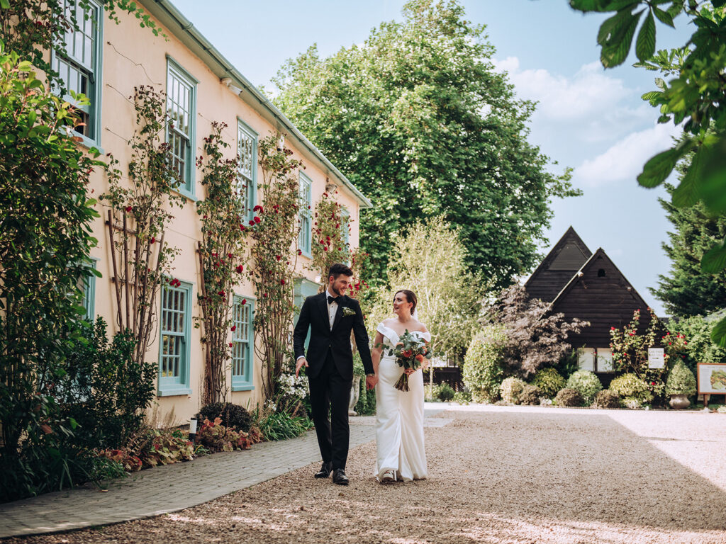 A photograph of a couple walking around the outside of the front of their wedding venue, behind the scenes of Editorial Wedding Photography: A Luxury Couple's Shoot