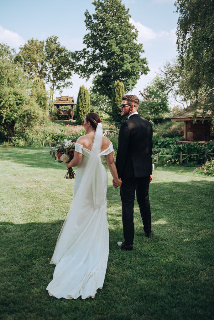 A couple exploring the gardens and looking over at guests at their luxury wedding venue, behind the scenes of Editorial Wedding Photography: A Luxury Couple's Shoot