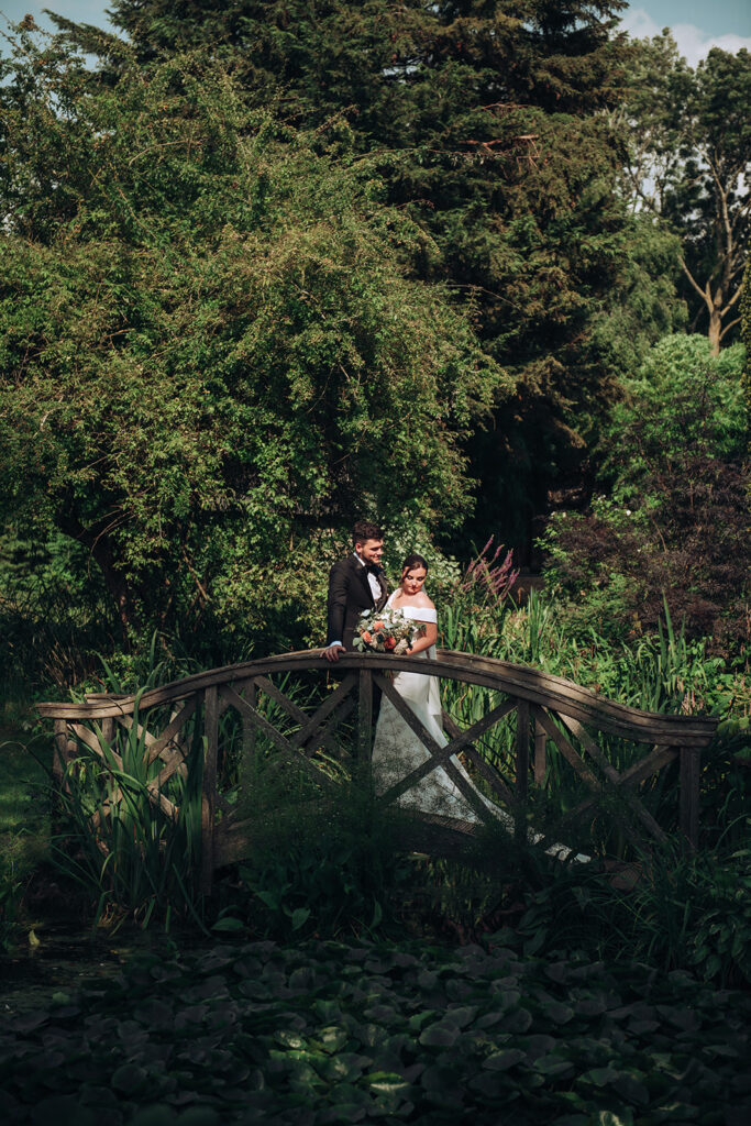 A couple standing on a bridge at their luxury wedding venue, behind the scenes of Editorial Wedding Photography: A Luxury Couple's Shoot