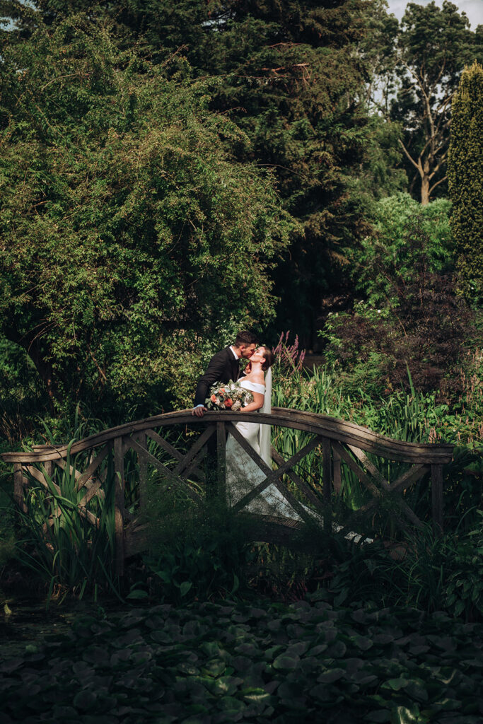 A couple kissing on a bridge at their luxury wedding venue, behind the scenes of Editorial Wedding Photography: A Luxury Couple's Shoot