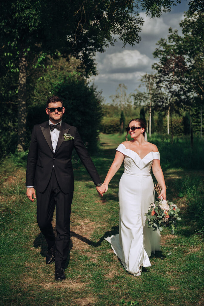 A couple walking hand in hand wearing sunglasses at their luxury wedding venue, behind the scenes of Editorial Wedding Photography: A Luxury Couple's Shoot