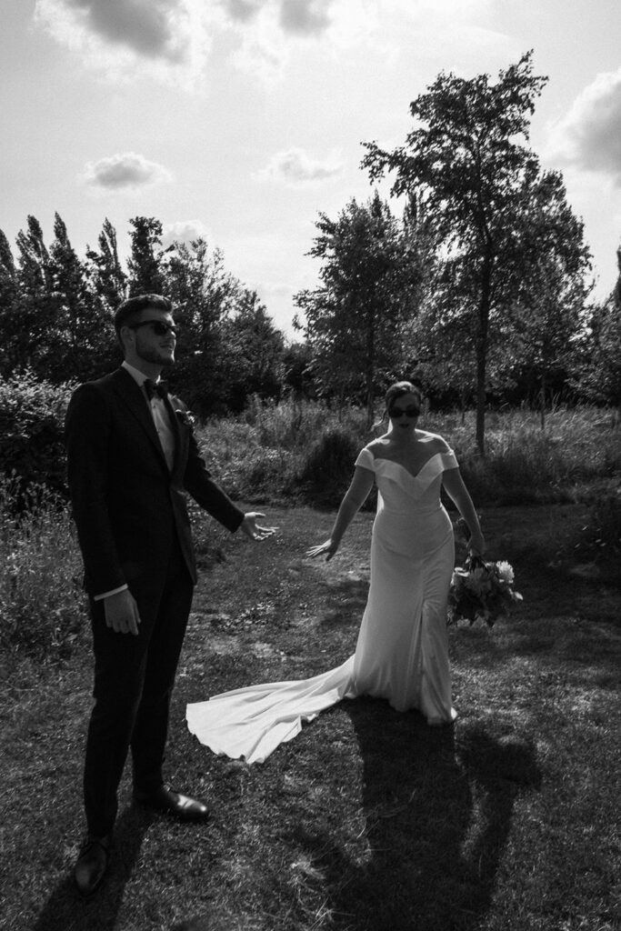 A couple walking hand in hand wearing sunglasses at their luxury wedding venue, behind the scenes of Editorial Wedding Photography: A Luxury Couple's Shoot in monochrome