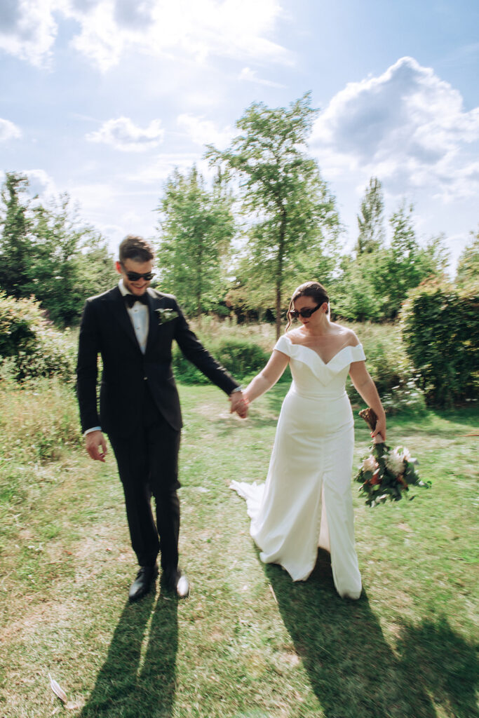 A couple walking hand in hand wearing sunglasses at their luxury wedding venue, behind the scenes of Editorial Wedding Photography: A Luxury Couple's Shoot